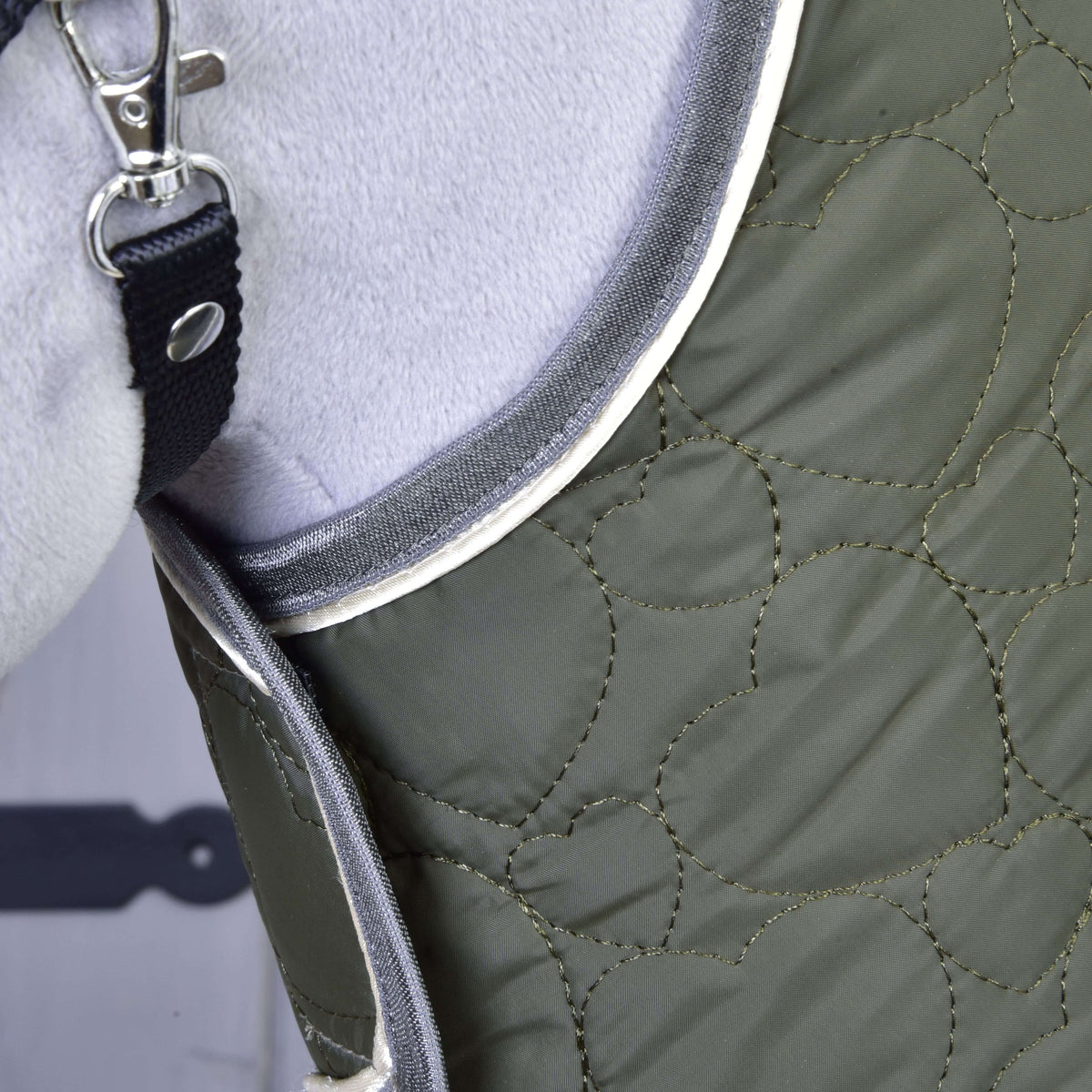 Close-up of the heart quilting and grey and cream piping at the neck of the olive Set Olivetti blanket on a Hobby Horse