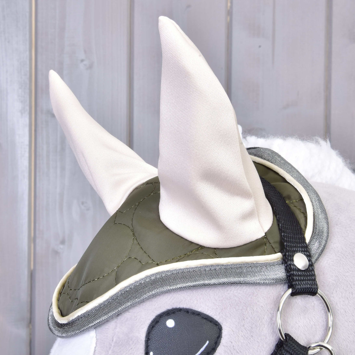 Close-up of the olive quilted ear bonnet with cream ears and grey piping from Set Olivetti on a grey Hobby Horse