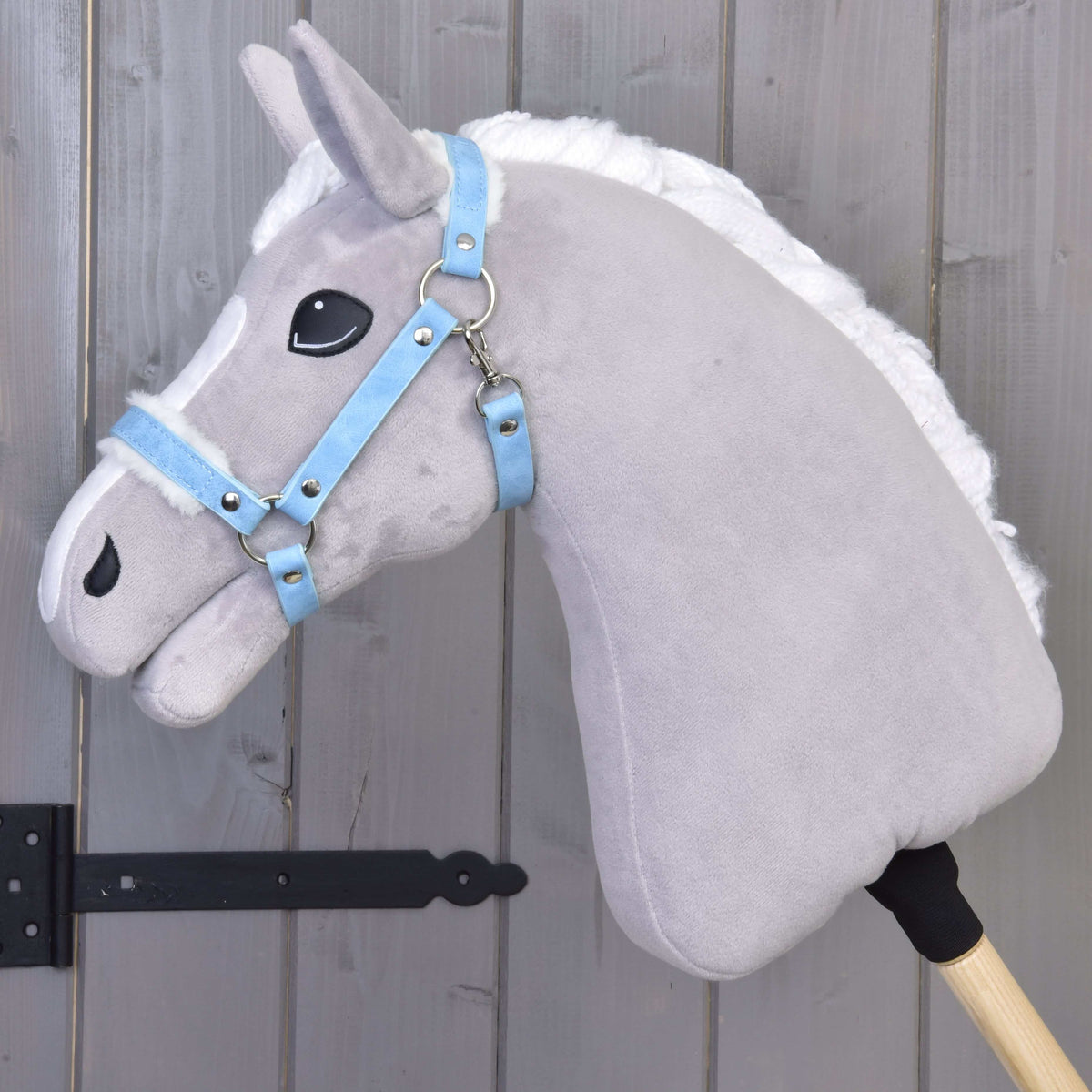 Siv Hobby Horse konj v levem profilu z oglavko s krznom Pastell Blue (umetno usnje), jermeni so podloženi z belim krznom