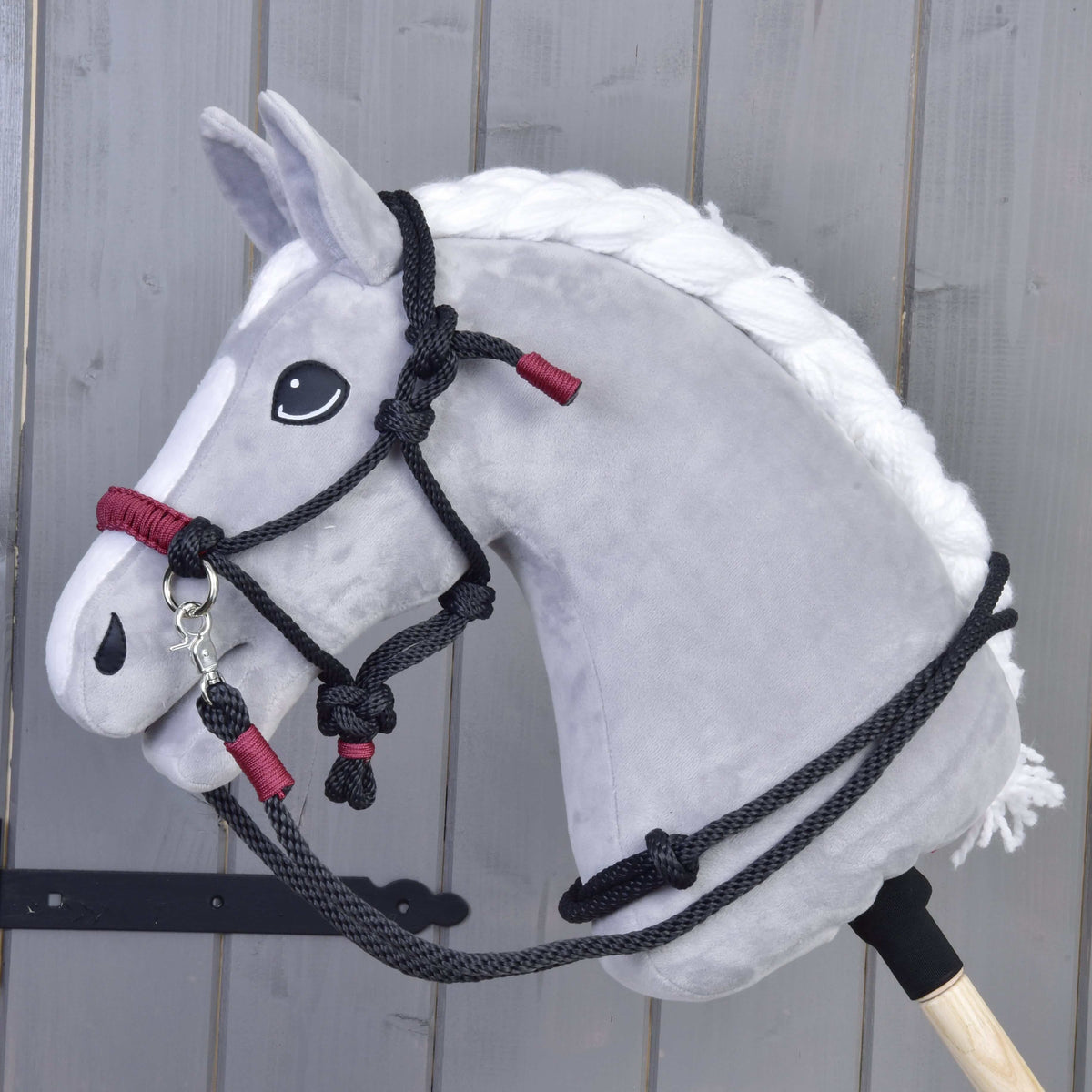 Siv Hobby Horse konj s spleteno belo grivo nosi vrvični komplet Maroon: črno vrvično oglavko in vajeti z bordo ovoji