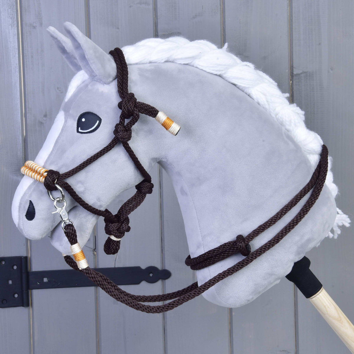 Siv Hobby Horse konj s spleteno belo grivo nosi oranžni vrvični komplet: temno rjavo vrvično oglavko in vajeti z oranžnimi ovoji