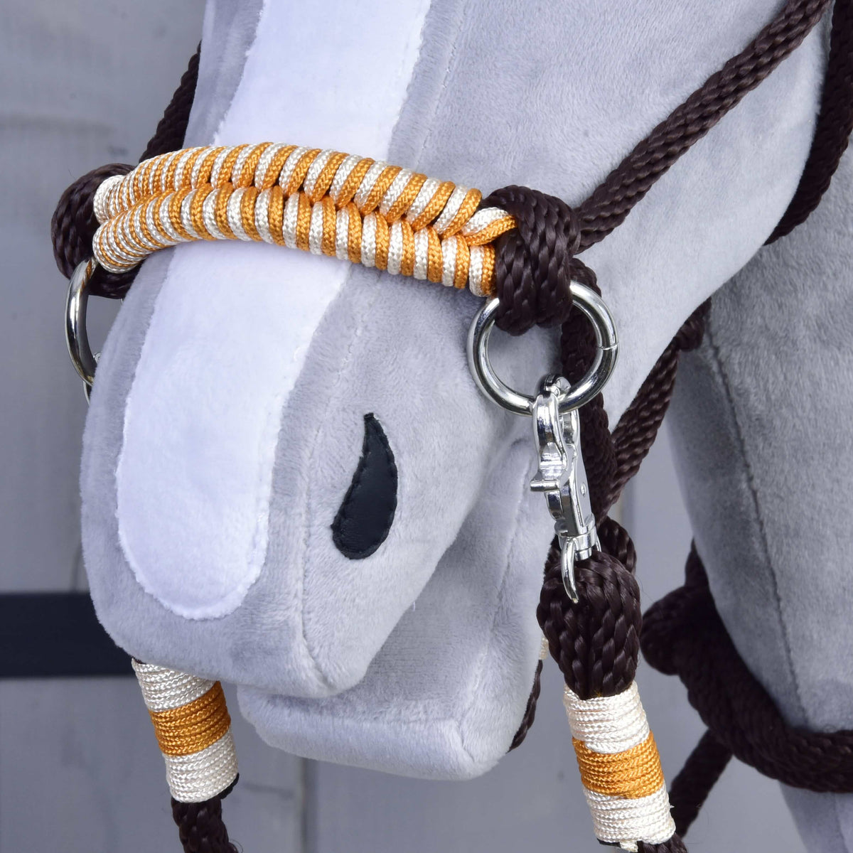 Bližnji posnetek nosnika iz oranžnega Hobby Horse vrvičnega kompleta, pletenega v oranžni in beli barvi, s srebrnim obročkom in karabinom