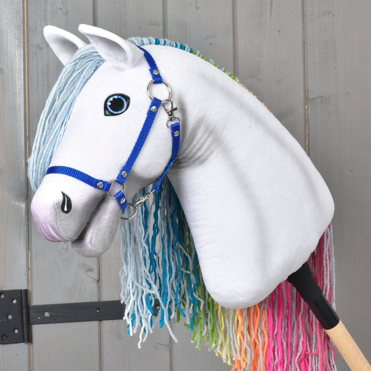Hobby Horse Rainbow v levem profilu: griva je na drugi strani, pod vratom se vidijo roza, oranžni in zeleni konci preje