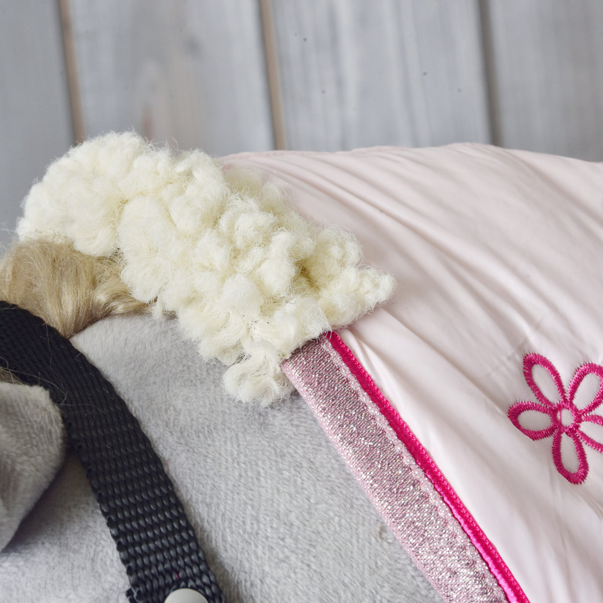 Close-up of the cream curly fleece collar and pink glitter trim of the Stable Blanket Rosy on a grey Hobby Horse