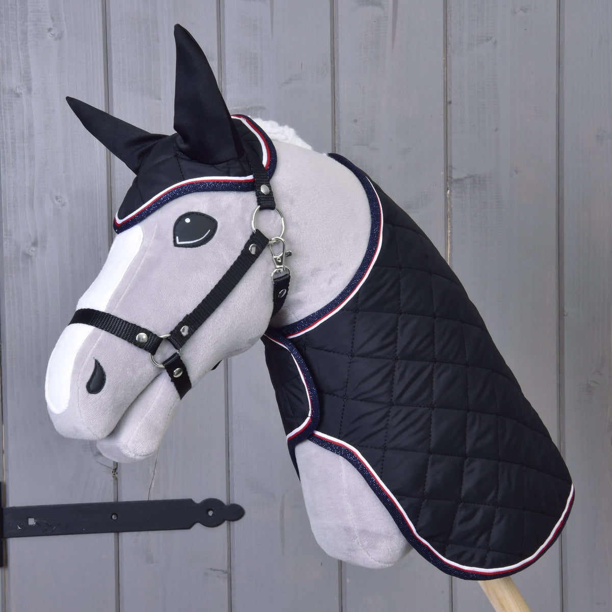 Grey plush Hobby Horse with a white blaze and black halter wearing the black quilted Set Royal blanket and ear bonnet