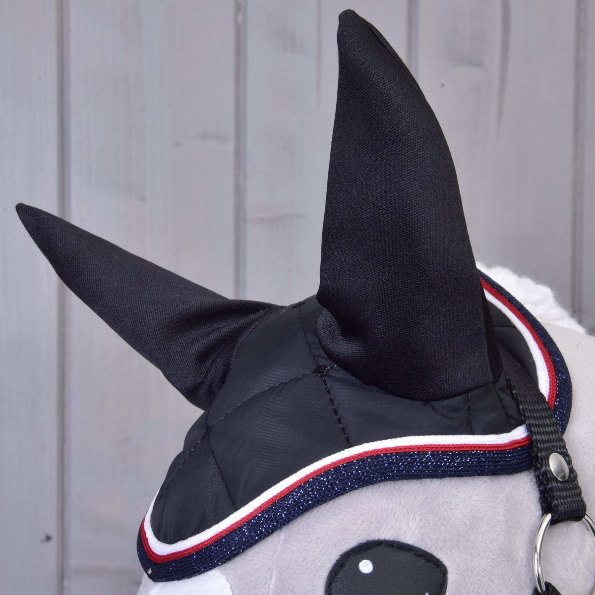 Close-up of the black Set Royal ear bonnet with tall black ears and glittery navy, red and white trim