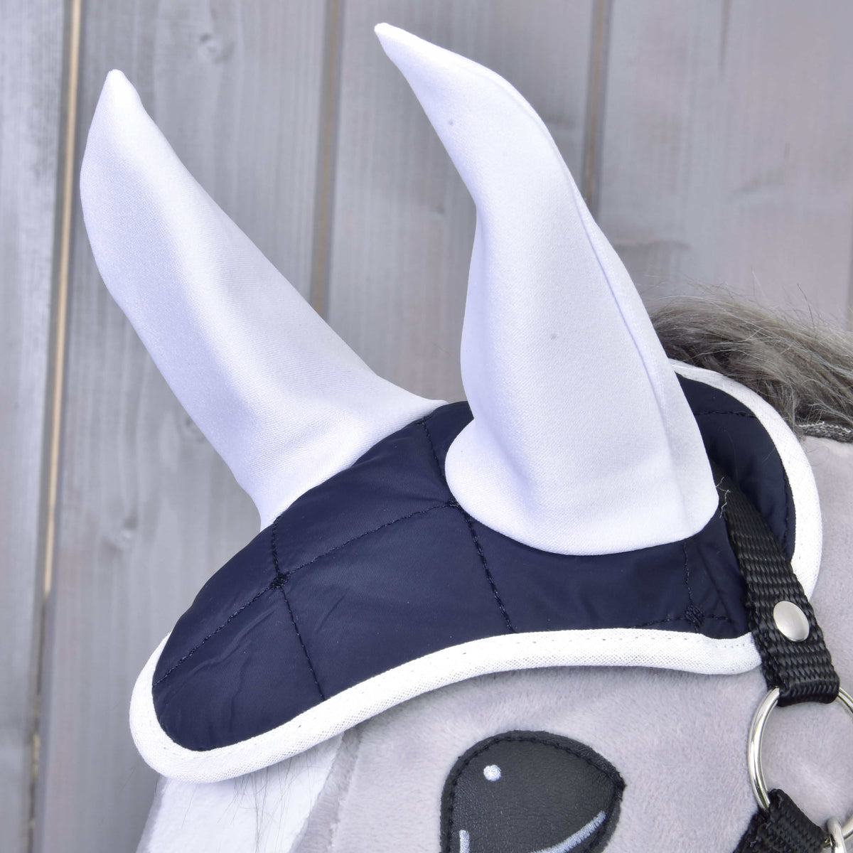 Close-up of the Set Monte ear bonnet with tall white ears, navy quilted crown and white binding on a grey Hobby Horse