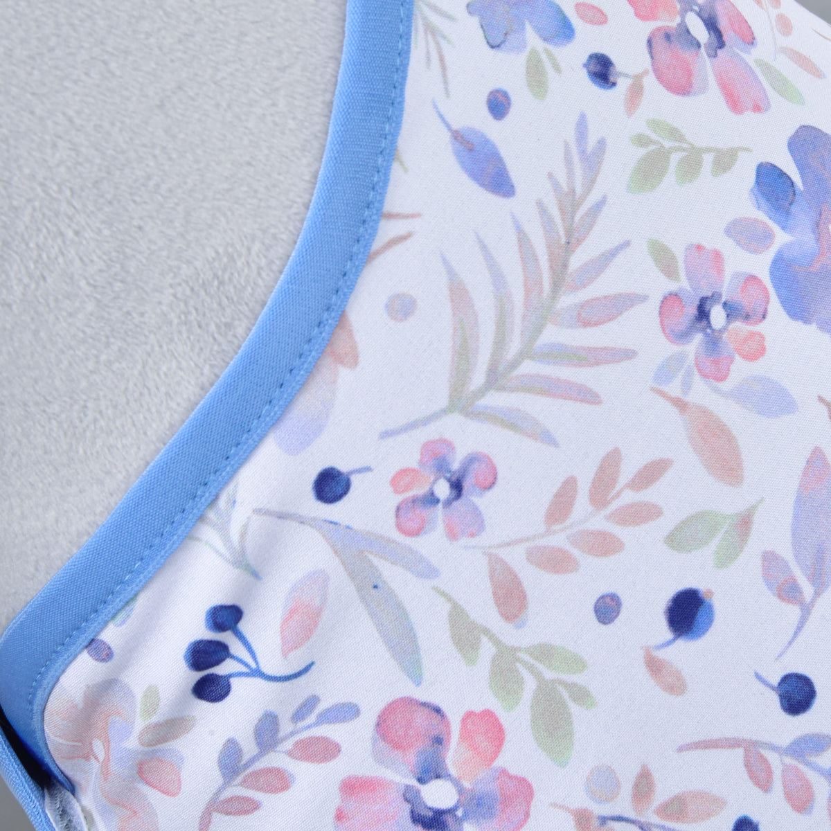 Close-up of the watercolour print with pink, lilac and navy flowers and soft leaves, edged in cornflower blue