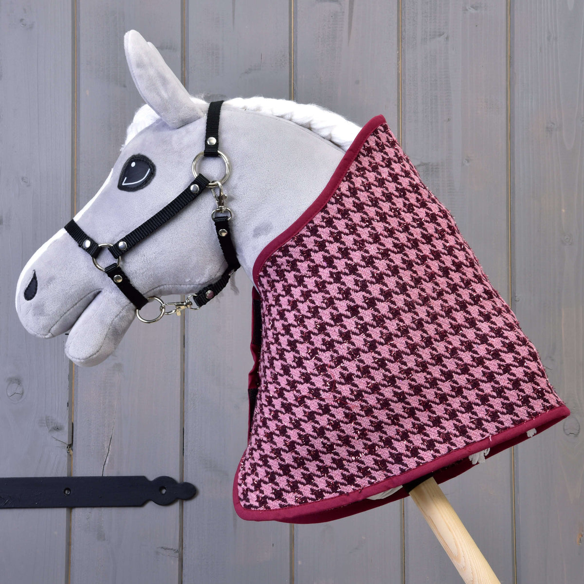 Grey Hobby Horse in a black halter wearing the pink and burgundy houndstooth blanket with burgundy binding
