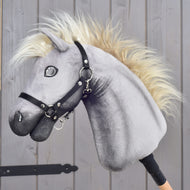 Hobby Horse Silver Dream znamke LarDen s sivo plišasto glavo, kremno grivo in črno oglavko, pogled od strani ob lesenih vratih hleva