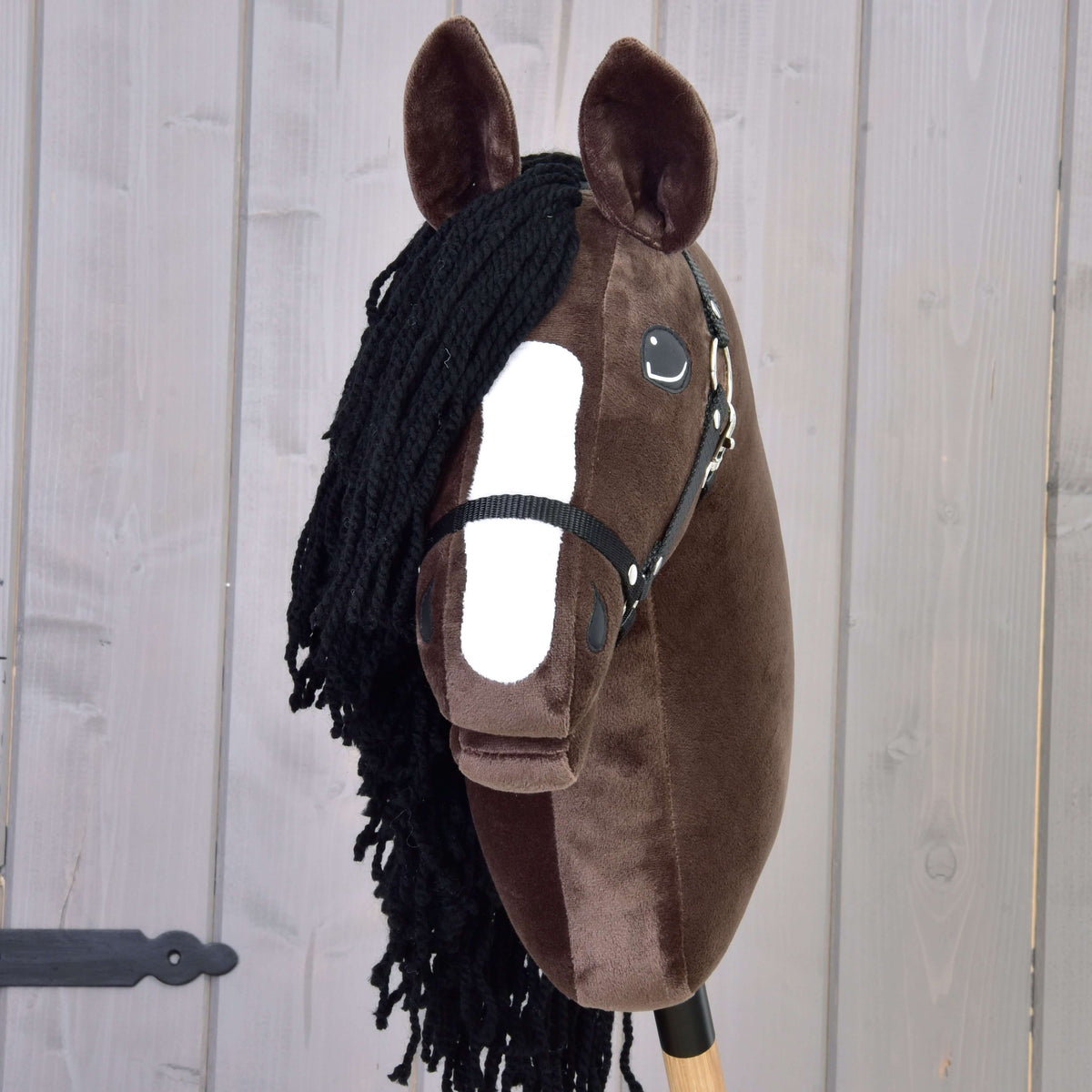 Front view of the dark brown Hobby Horse Sisi with a white blaze, black yarn forelock and black halter