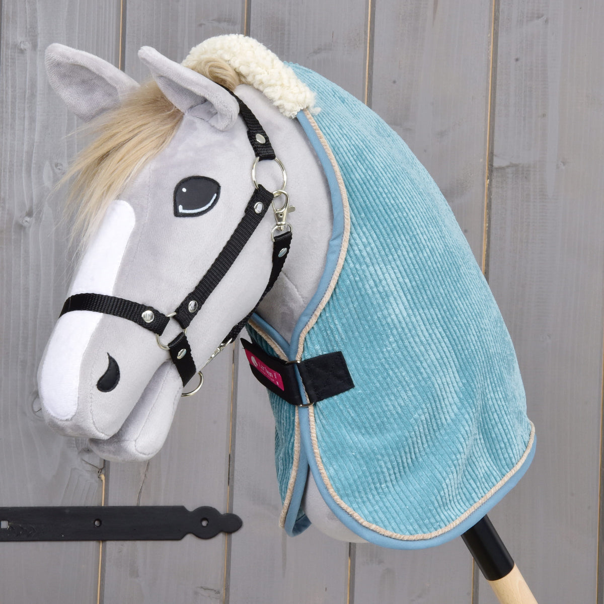 Light grey Hobby Horse with a black halter wearing the teal corduroy stable blanket with a cream teddy collar