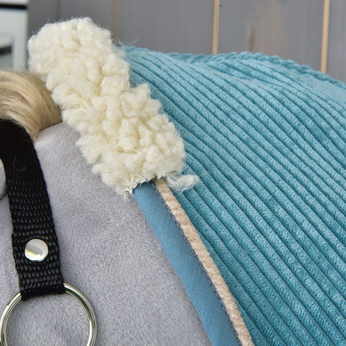 Close-up of the curly cream teddy fleece collar on the teal corduroy blanket with blue binding and beige piping
