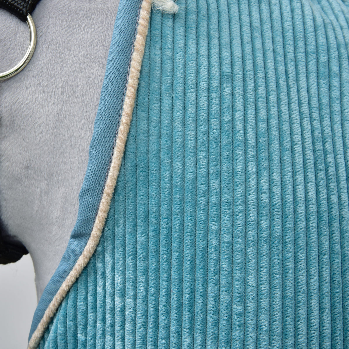 Close-up of the wide teal corduroy ribs with blue binding and beige piping along the edge by the halter ring