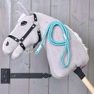 Svetlo siv Hobby Horse konj s črno oglavko in turkiznim povodcem Atlantis, prevešenim čez vrat