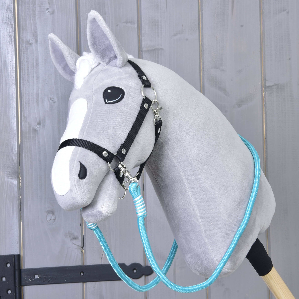 Svetlo siv Hobby Horse konj s črno oglavko in turkiznimi vajetmi Atlantis, ovitimi okoli vratu