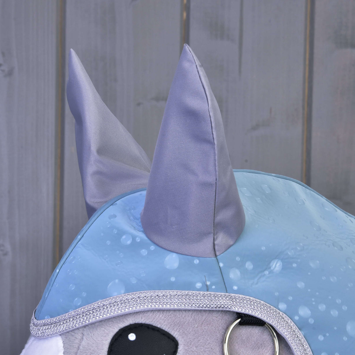 Close-up of the grey satin ears and silver glitter edging of the Raincoat Blue Drops on a grey Hobby Horse