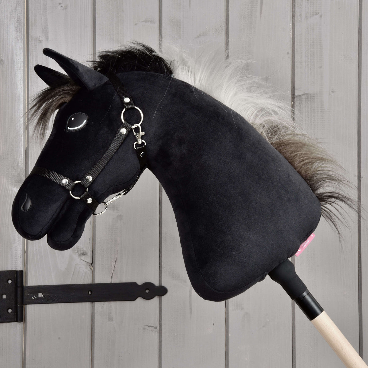 Hobby Horse Bond with Black Halter in full profile on its wooden stick, silver-grey mane falling down the black neck