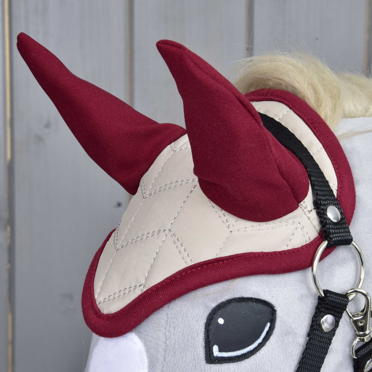 Close-up of the Ear Bonnet Maroon Star on a grey Hobby Horse: maroon ear covers and cream quilting with maroon binding
