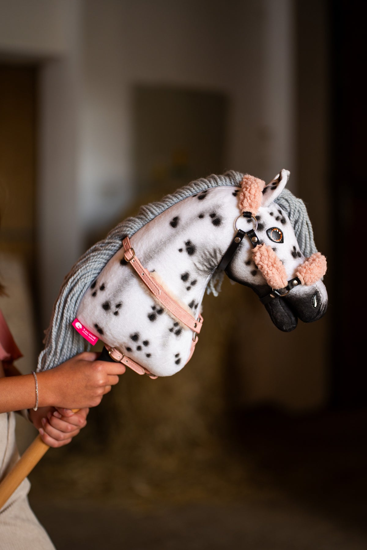 Hobby Horse konj Chantal od blizu v oglavki z breskovo roza krznom in pudrasto roza oprsnico, črne pike na belem vratu