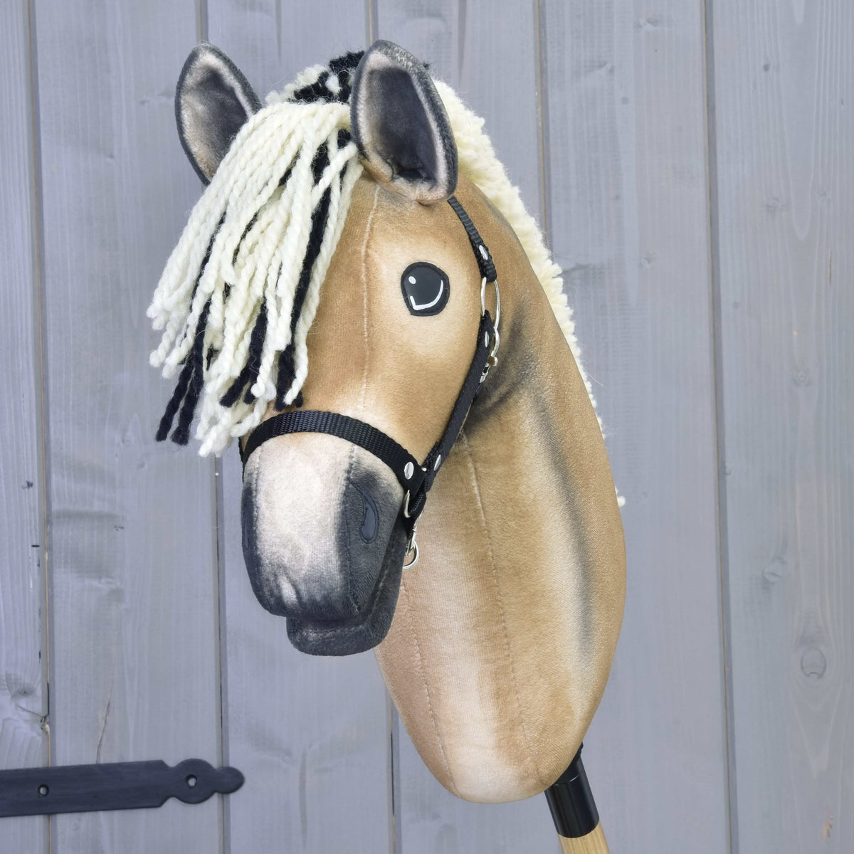 Pogled od spredaj na Hobby Horse konja Colby s kremno-črnim čopom iz preje, temnimi konicami ušes in črno oglavko