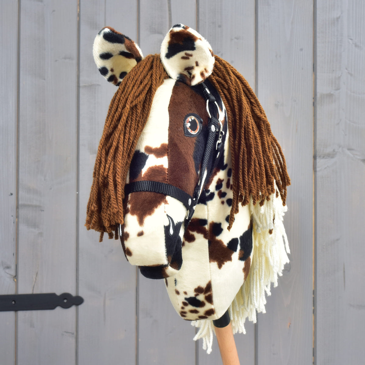 Hobby Horse Dakota s črno oglavko od spredaj: rjav čop iz preje in pikasta ušesa nad jantarnimi očmi