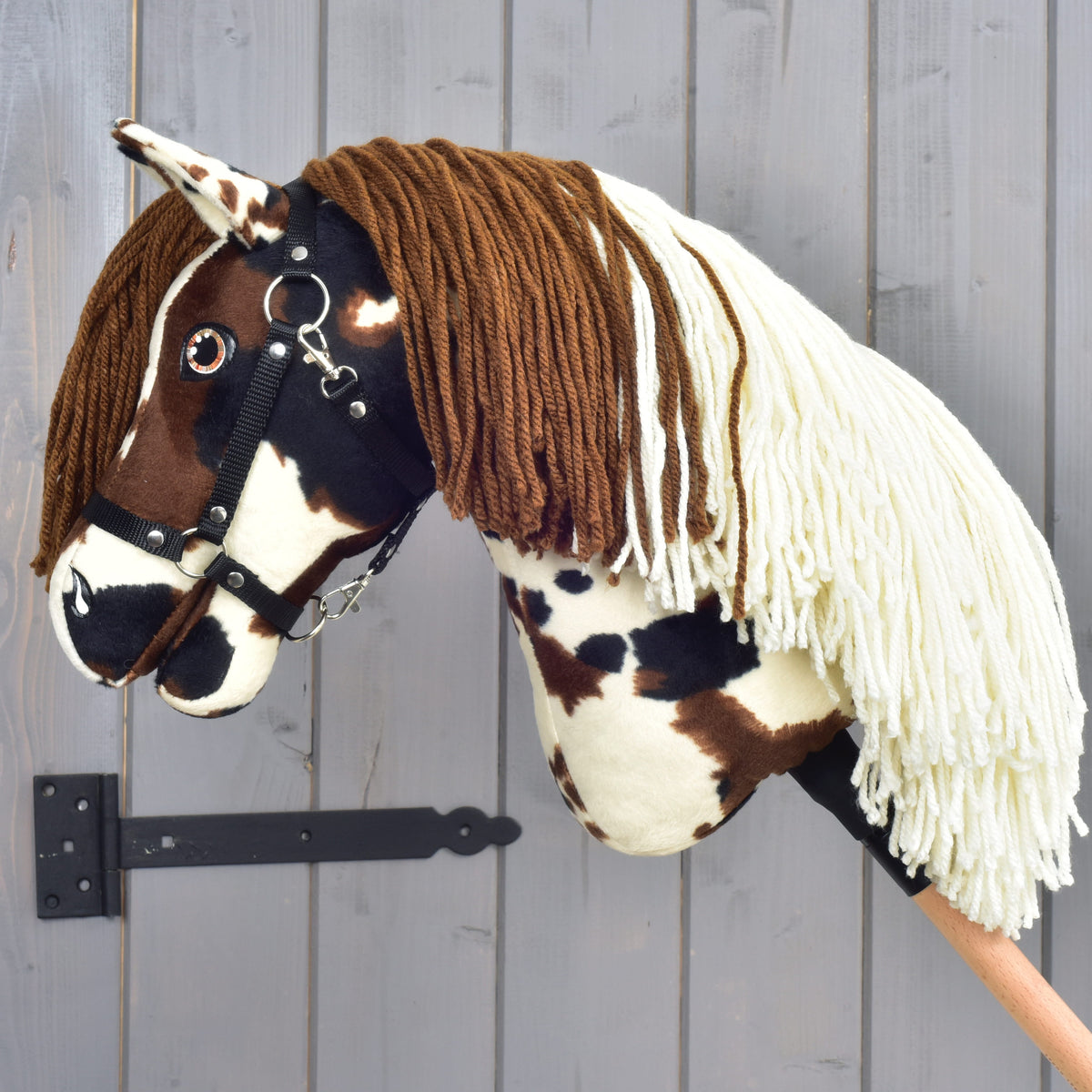 Hobby Horse Dakota s črno oglavko, obrnjen v levo: dvobarvna griva iz rjave in kremne preje, ki pada čez vrat