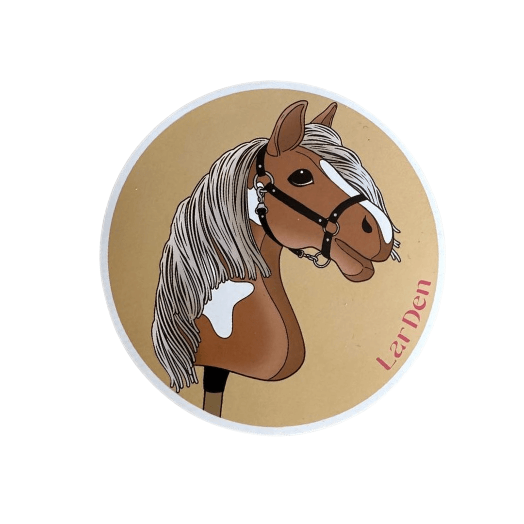 Sticker with a brown and white pinto Hobby Horse, long grey mane and black halter on a sand-coloured circle