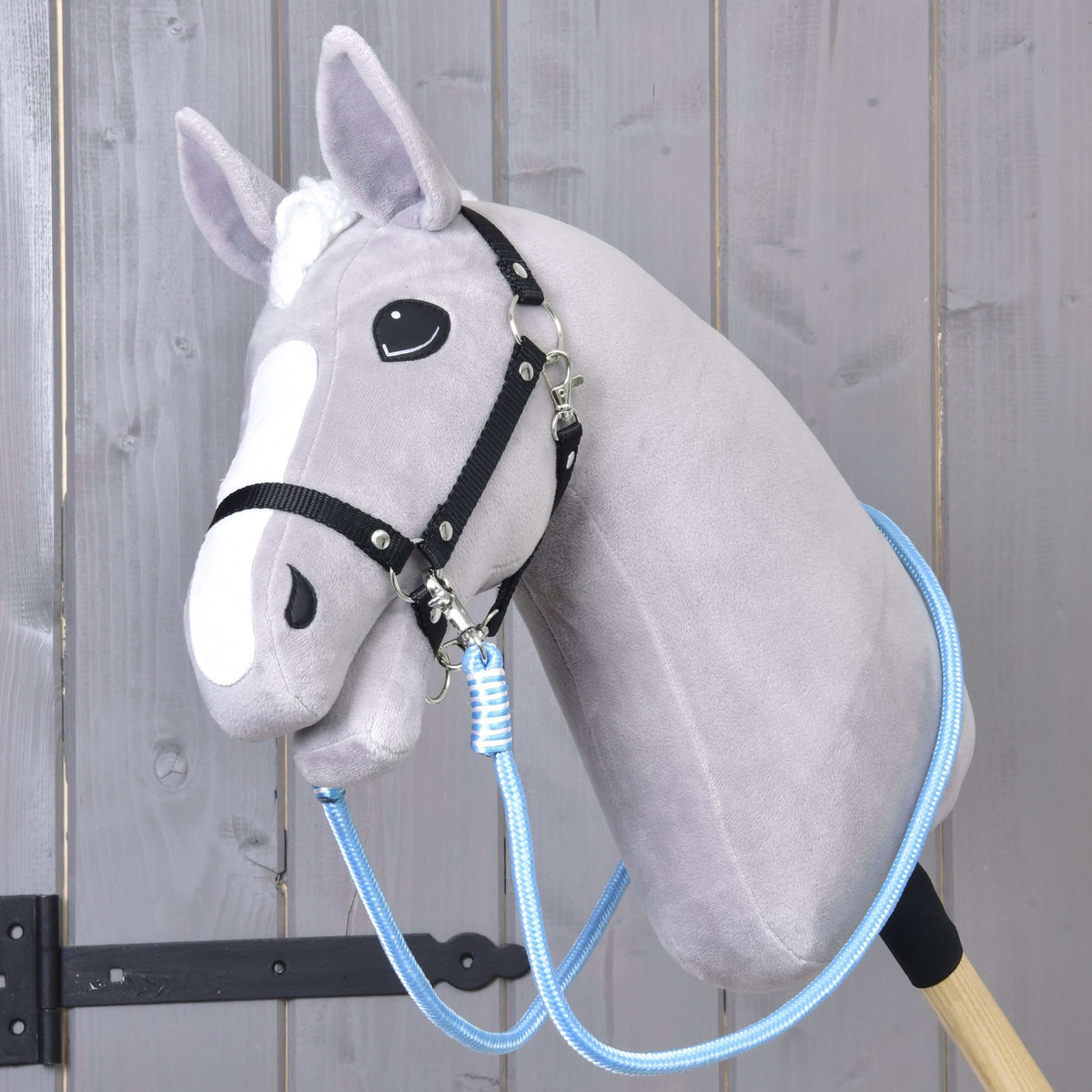 Svetlo siv Hobby Horse konj s črno oglavko in svetlo modrimi vajetmi Heaven, pripetimi pod brado