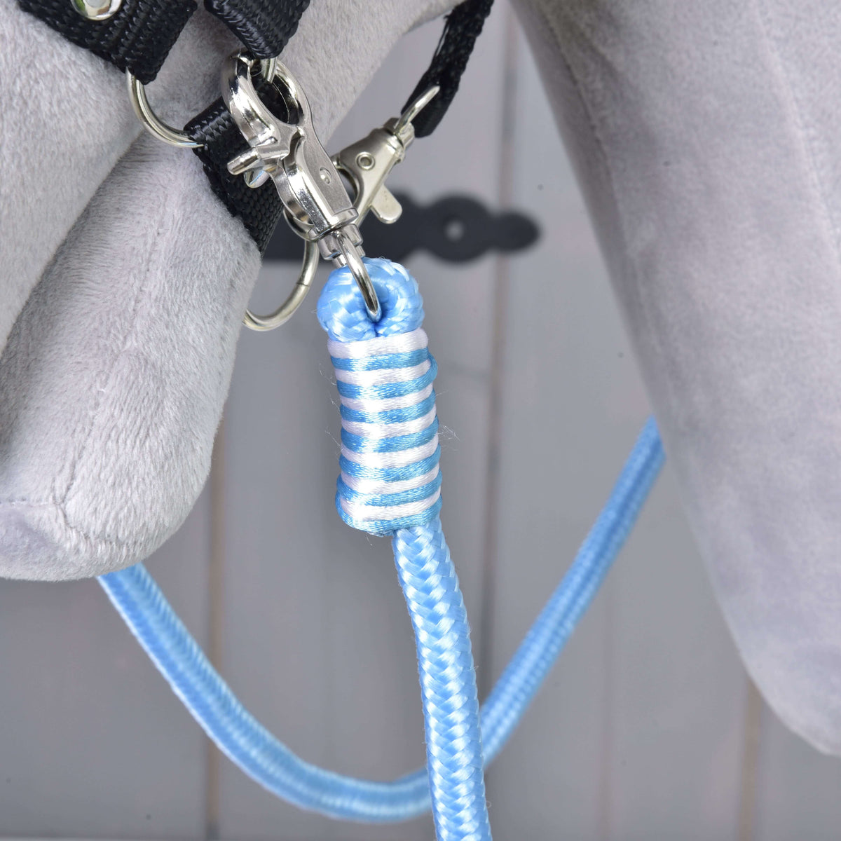 Bližnji posnetek modro-belega ovoja in srebrnega karabina Hobby Horse vajeti Heaven na črni oglavki