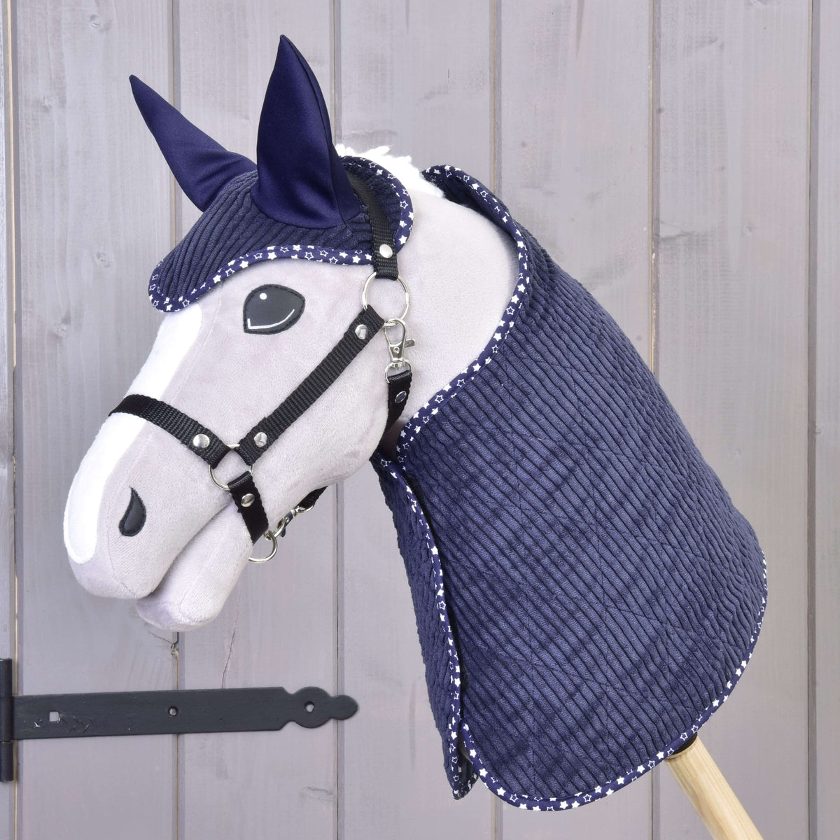 Siv Hobby Horse konj s črno oglavko, oblečen v temno modro pregrinjalo iz rebrastega žameta in naušnike z obrobo s potiskom zvezdic