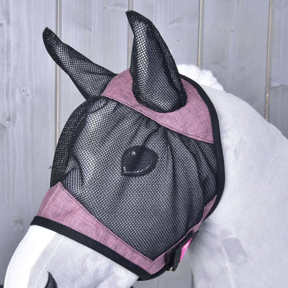 Bližnji posnetek maske proti mrčesu na sivem Hobby Horse konju od strani: črna mrežica čez oko in roza trakovi s črno obrobo