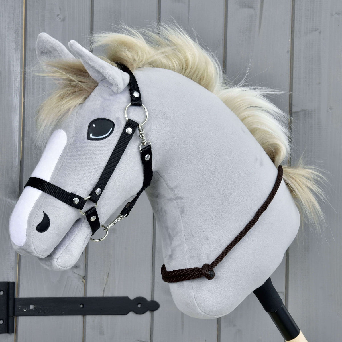 Svetlo siv Hobby Horse konj s smetanasto grivo in črno oglavko nosi nizko okoli vratu vratni obroč Chocolate