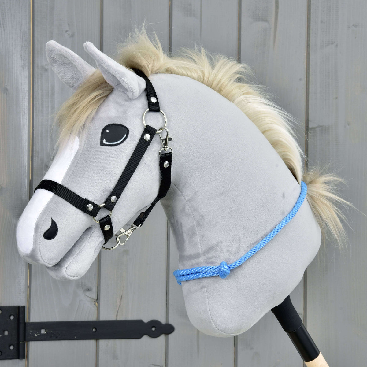 Svetlo siv Hobby Horse konj s smetanasto grivo in črno oglavko nosi vratni obroč Sky, modro vozlano vrv nizko na vratu