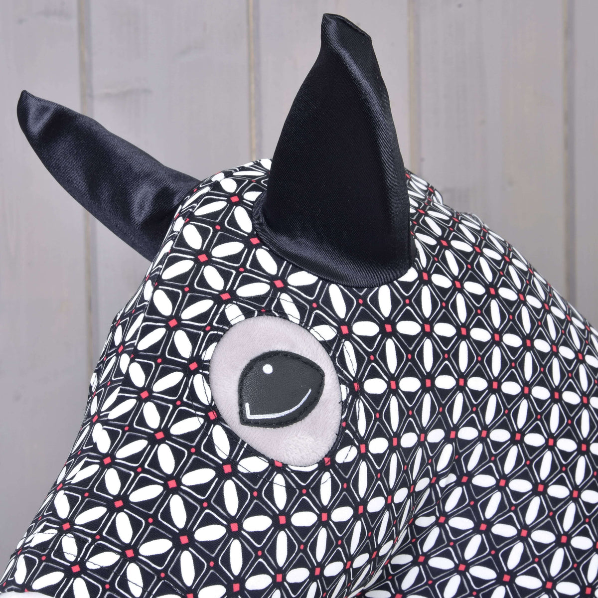 Close-up of the Hobby Horse protective suit DeLuxe: black satin ear and eye opening in the geometric print