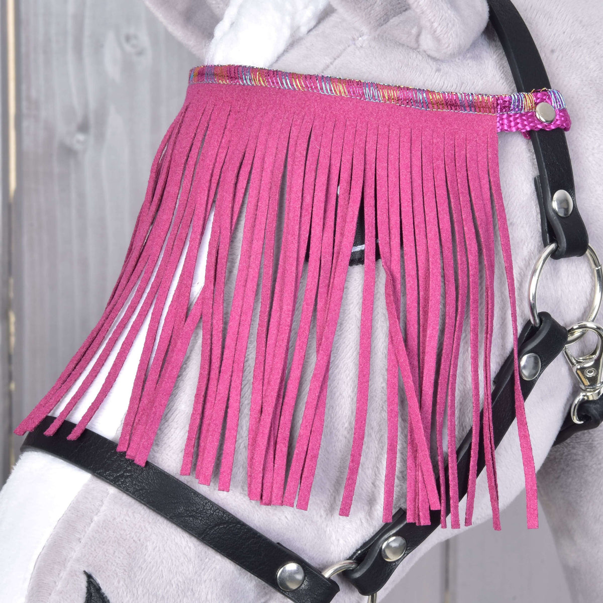 Bližnji posnetek roza res, ki pokrivajo oko sivega Hobby Horse konja, obešenih na lesketajočem se traku črne oglavke