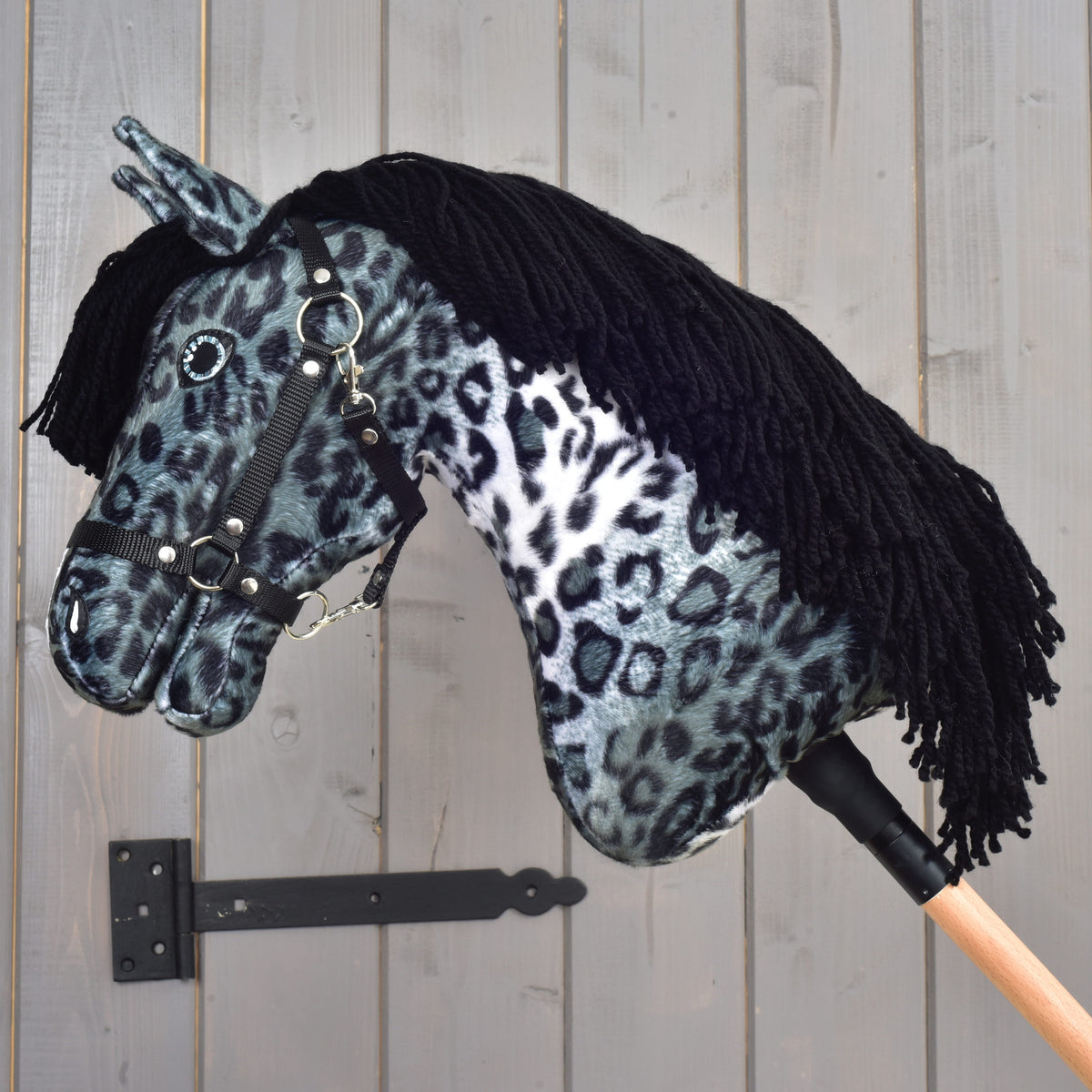 Hobby Horse Picasso s črno oglavko v profilu s sklonjeno glavo in črno grivo iz preje, ki visi čez vrat