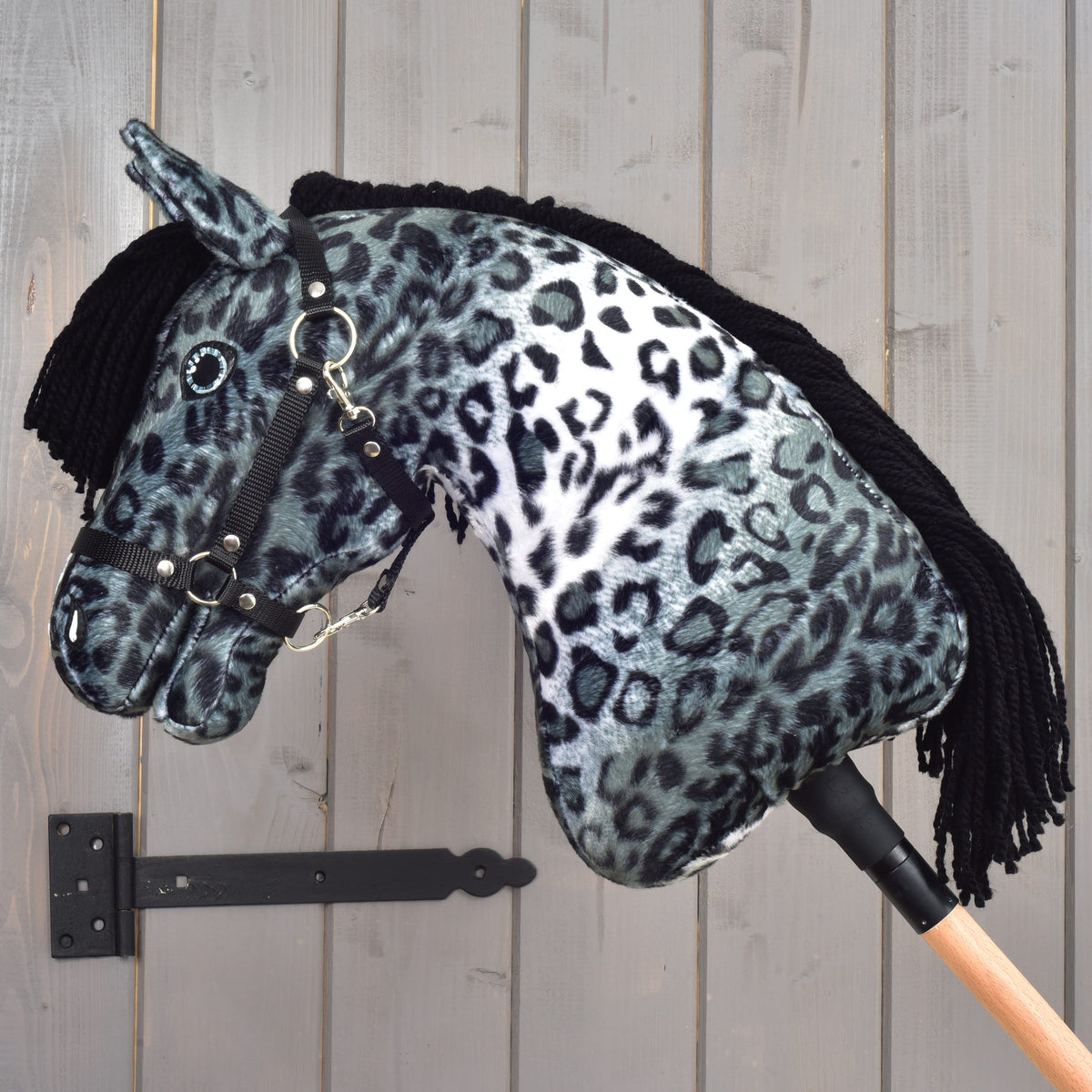 Hobby Horse Picasso s črno oglavko, obrnjen v levo, z usločenim vratom, črno grivo na drugi strani in srebrnimi obročki oglavke