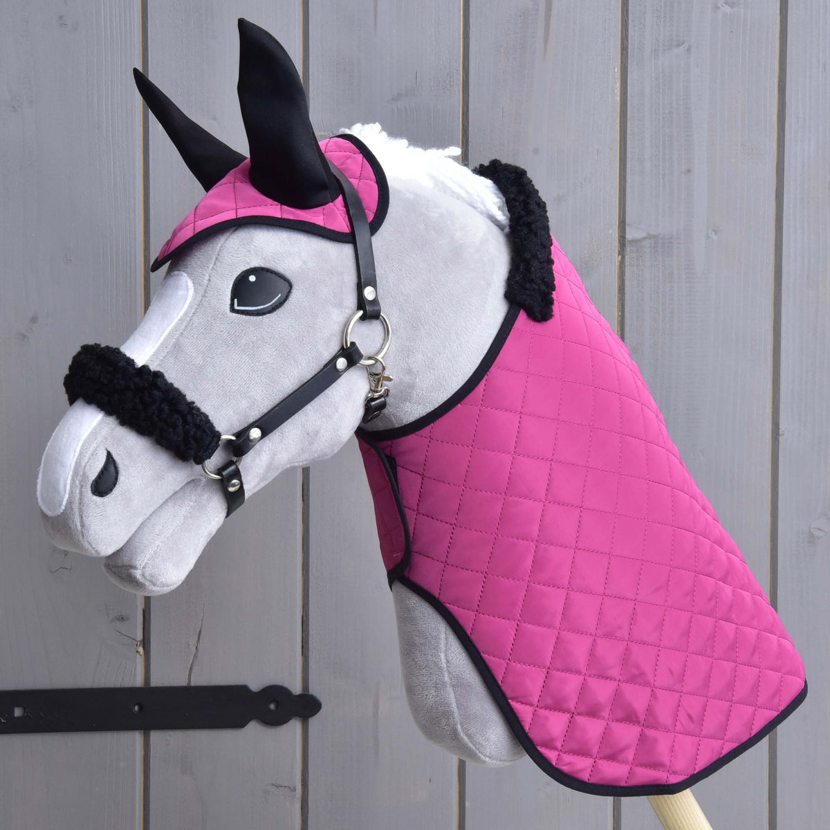 Grey Hobby Horse wearing the Set Pink Beauty: quilted pink blanket and ear bonnet with black ears plus a black fur halter