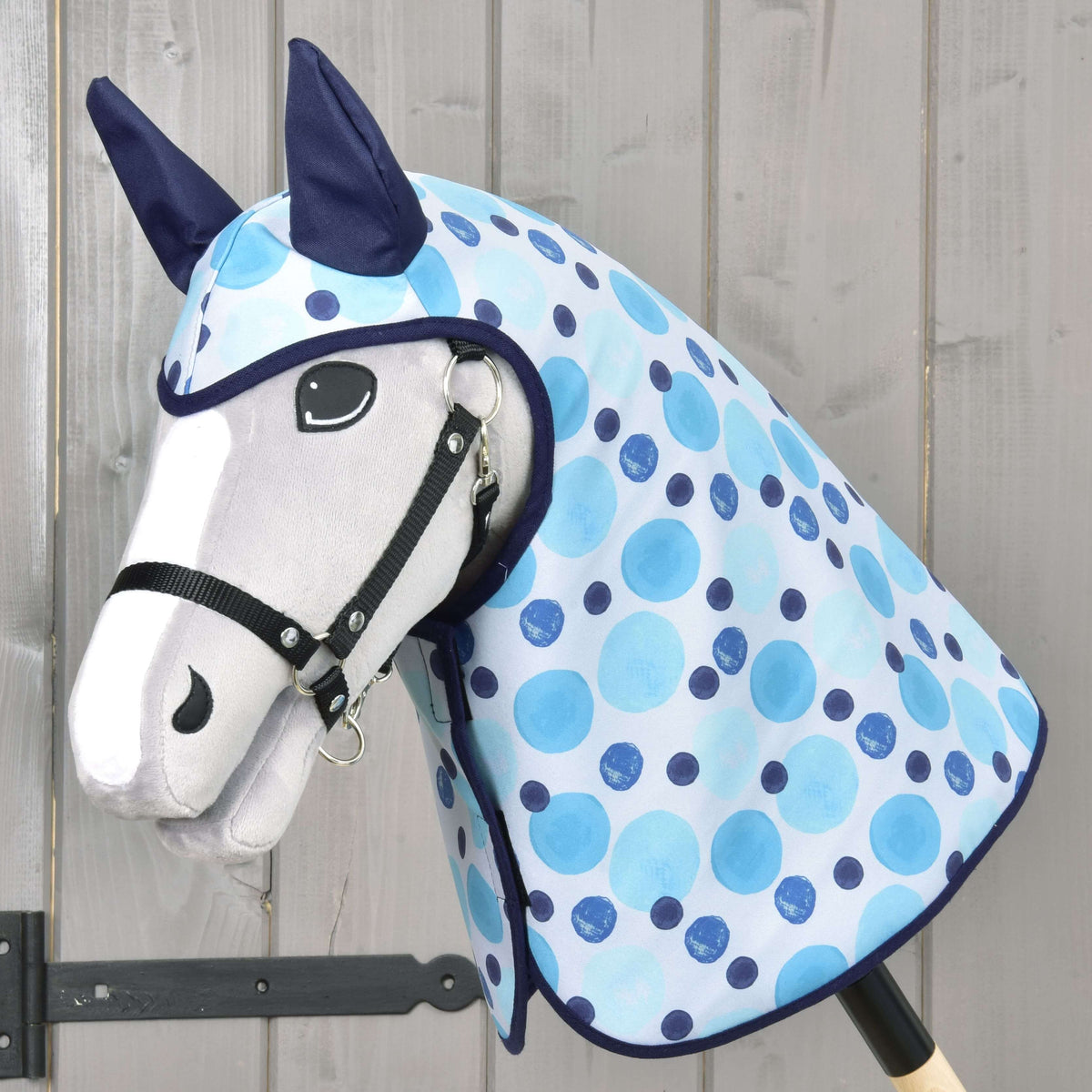 Light grey Hobby Horse in a black halter wearing the Raincoat Bubbles, light blue and navy dots with navy ears and trim