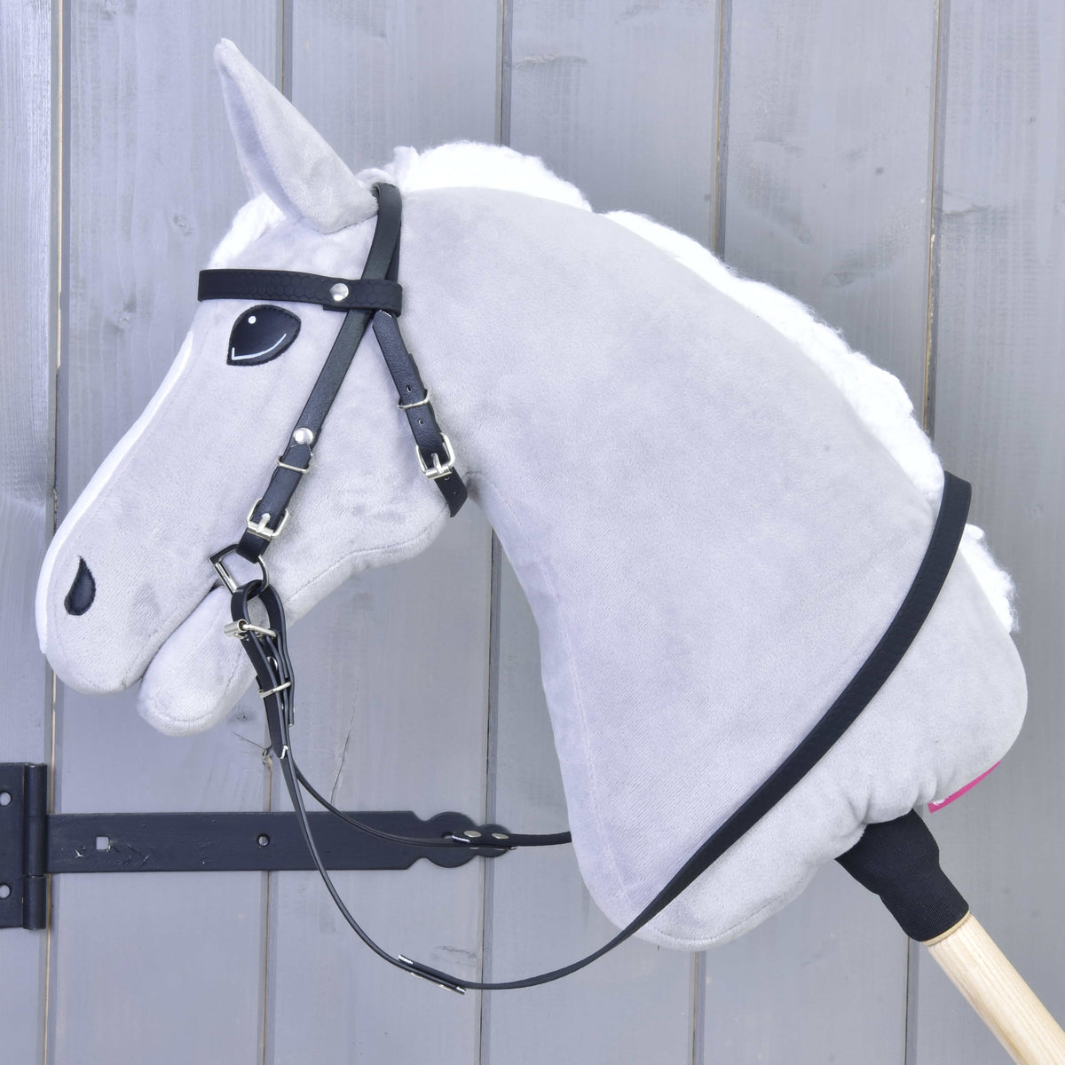 Grey Hobby Horse in left profile wearing the black leatherette bridle, the reins resting over its neck
