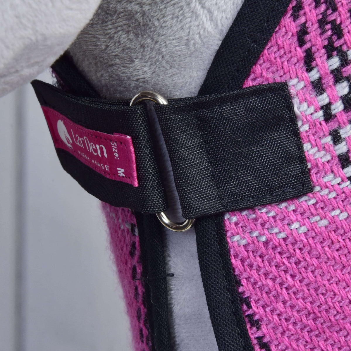 Zapenjanje na prsih pregrinjala iz kompleta Harmony Pink: črn trak, kovinski obroček, roza etiketa LarDen in črna obroba