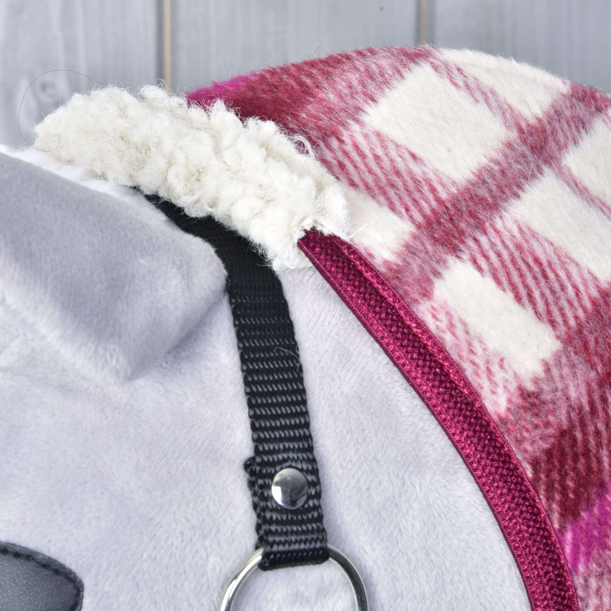 Close-up of the fluffy cream sherpa trim at the top of the checked blanket, next to the black halter strap