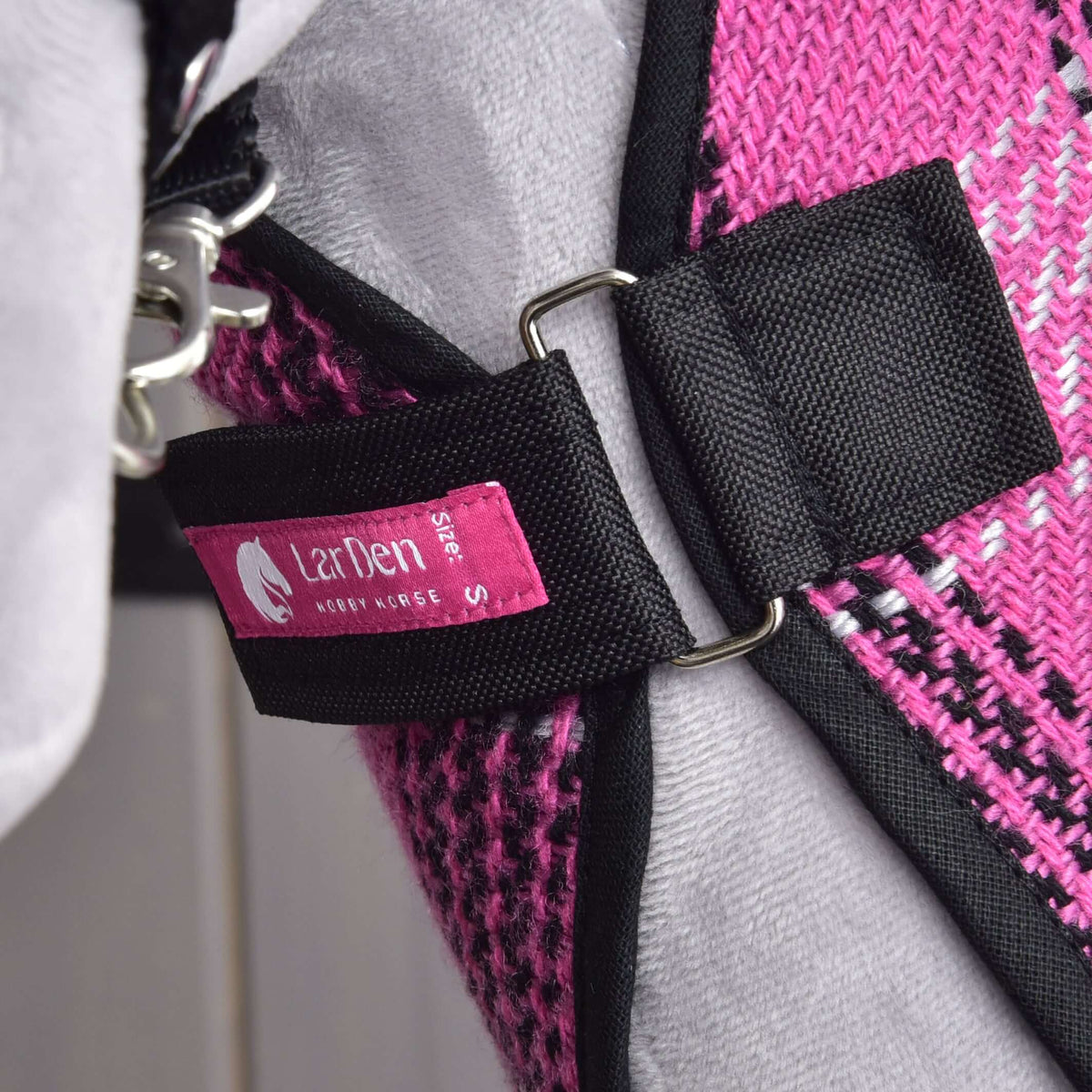 Chest strap of the Hobby Horse Stable Blanket Pink fastened on a grey plush chest, with D-rings and the pink LarDen label
