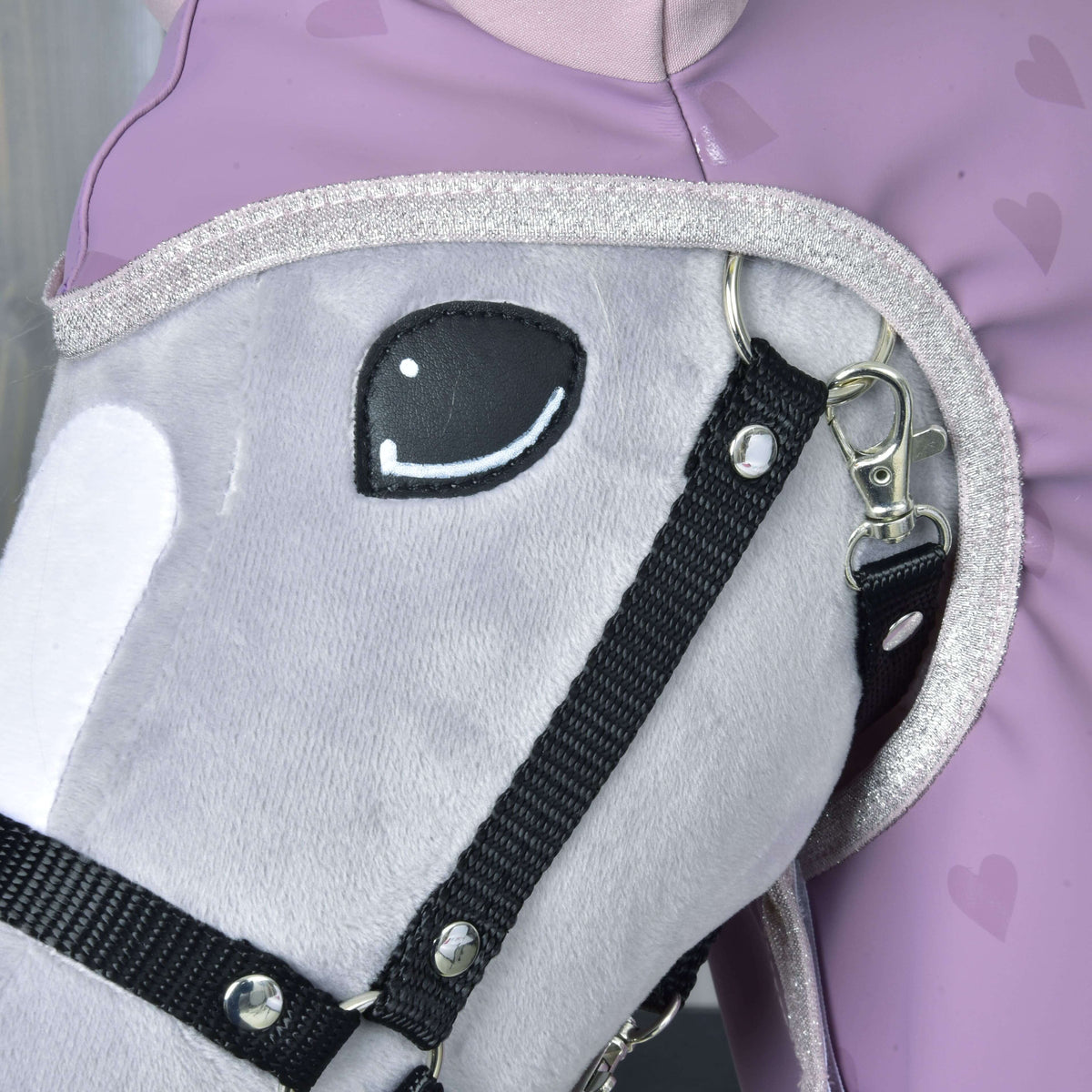 Bližnji posnetek dežnega pregrinjala Sweetheart: srebrna bleščeča obroba okoli glave sivega Hobby Horse konja s črno oglavko