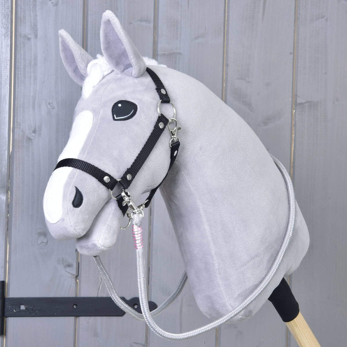 Svetlo siv Hobby Horse konj s črno oglavko in sivimi vajetmi Tizian z roza ovoji, pripetimi pod brado
