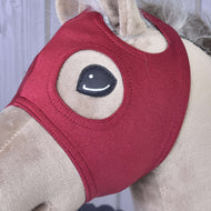 Bližnji posnetek bordo maske brez ušes na bež Hobby Horse konju z obšito okroglo odprtino za oko in odprtino za uho
