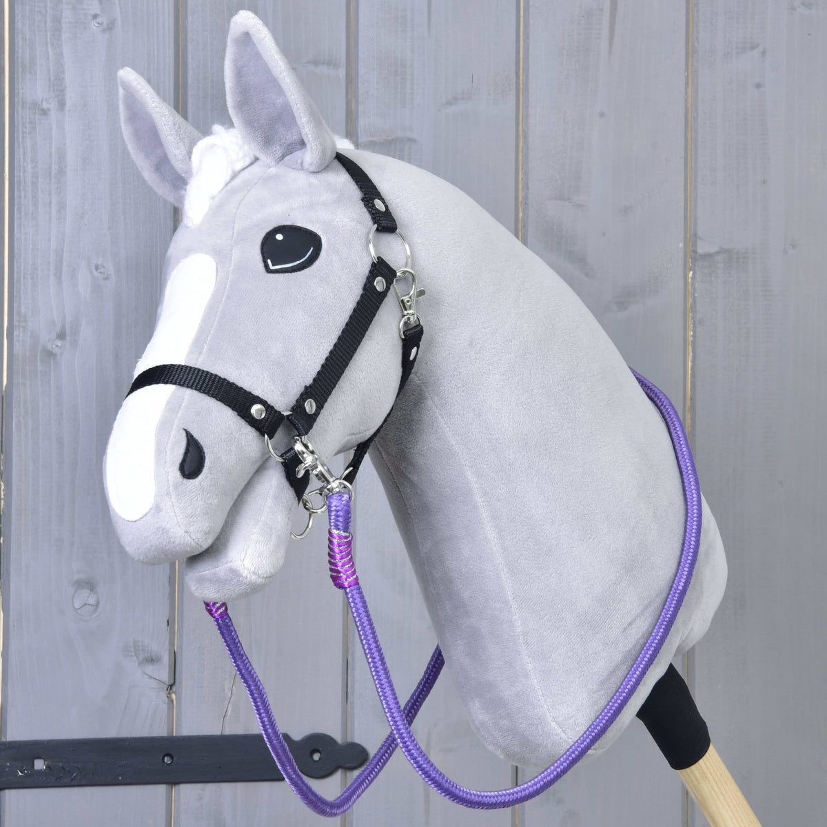 Svetlo siv Hobby Horse konj s črno oglavko in vijoličnimi vajetmi Viola, pripetimi na obe strani oglavke