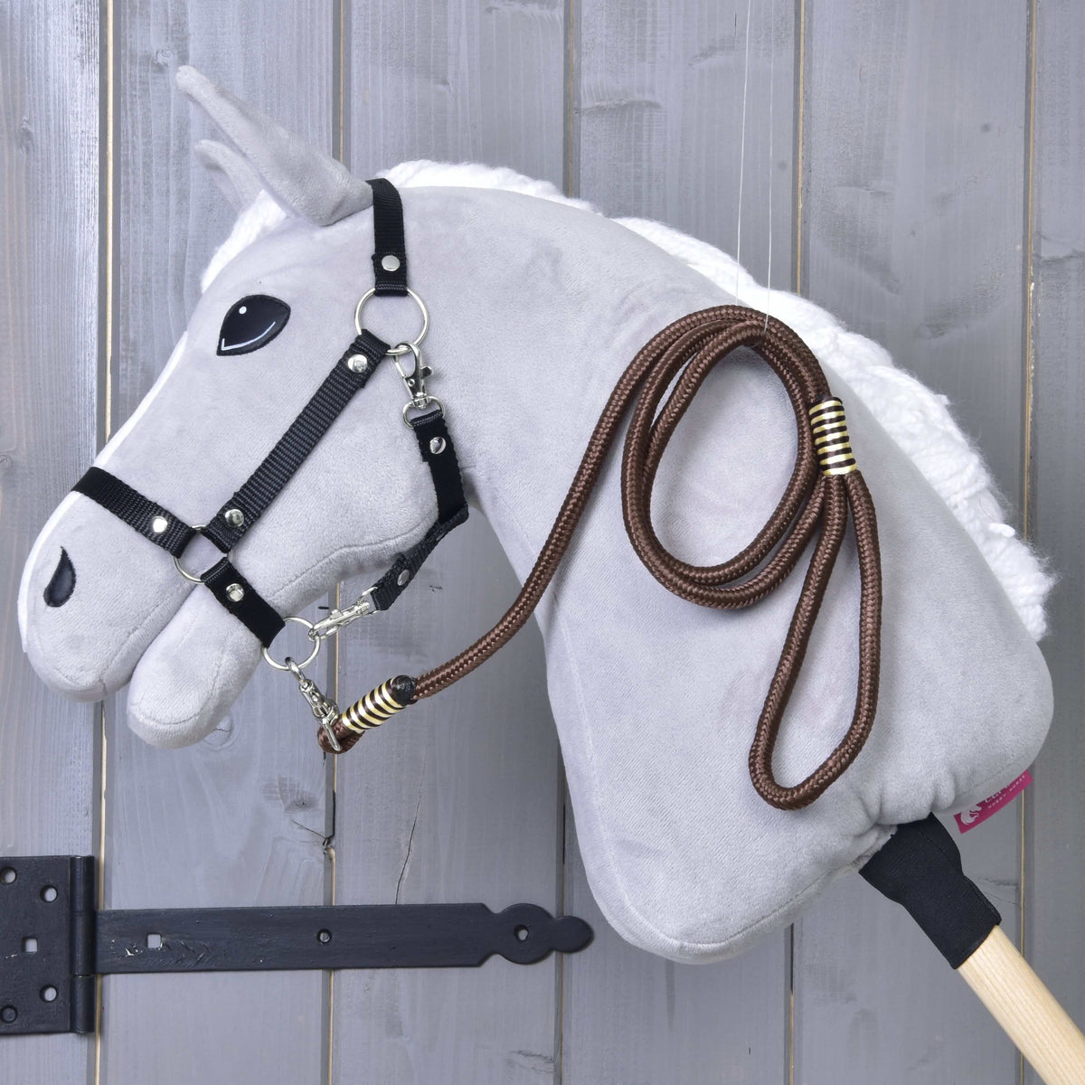 Light grey Hobby Horse in a black halter with the brown rope stripe Vivaldi lead rope draped over its neck