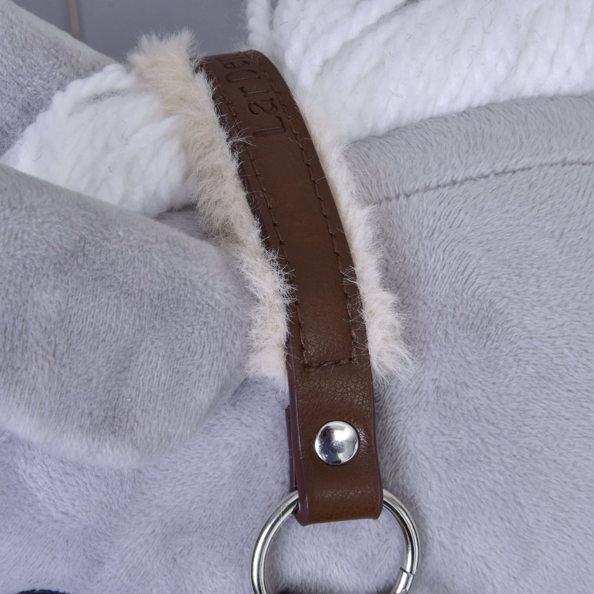 Close-up of the brown crownpiece with embossed lettering and cream fur lining next to the white yarn mane